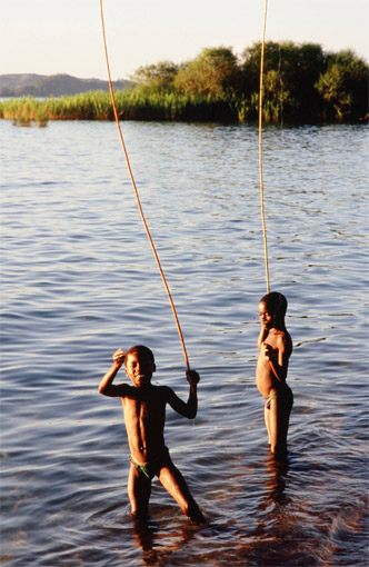 Local children bathing the late afternoon sun near reeds in Lago Niassa, Mozambique: this is peak transmission time for schistosomiasis and an ideal habitat for water snails.
